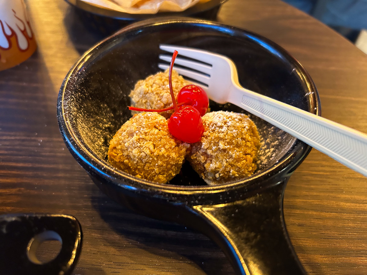 little dessert balls of dough with a fork and cherries